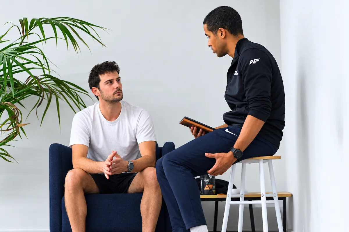 Entretien individuel et bilan personnalisé entre un coach Anytime Fitness et un membre dans l'espace consultation.