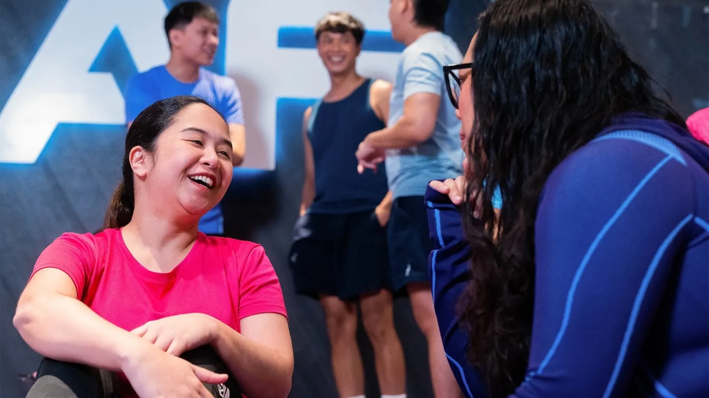 Gym members smiling and chatting inside an Anytime Fitness club.
