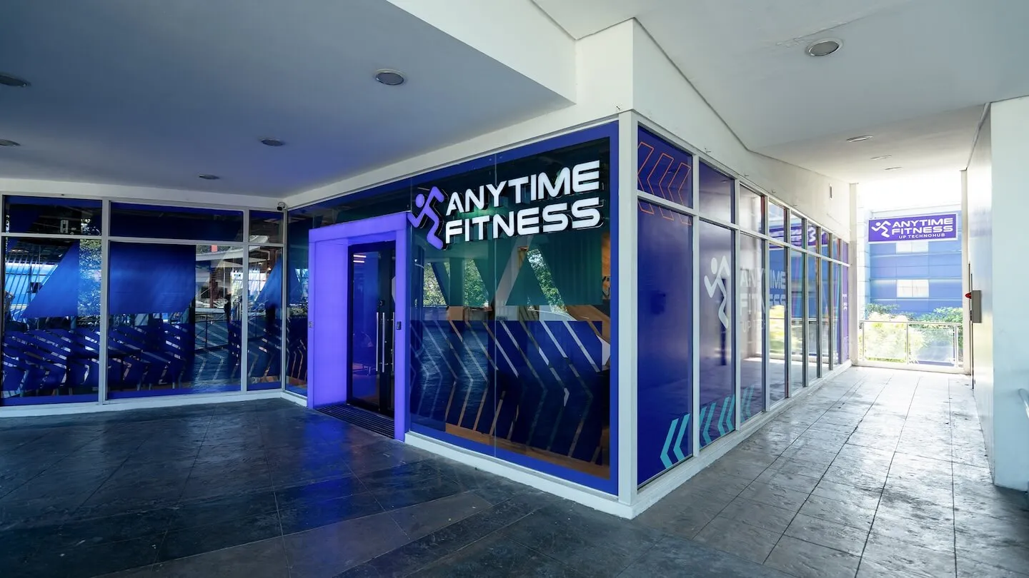 Entrance to Anytime Fitness UP Technohub with purple lighting and glass windows.