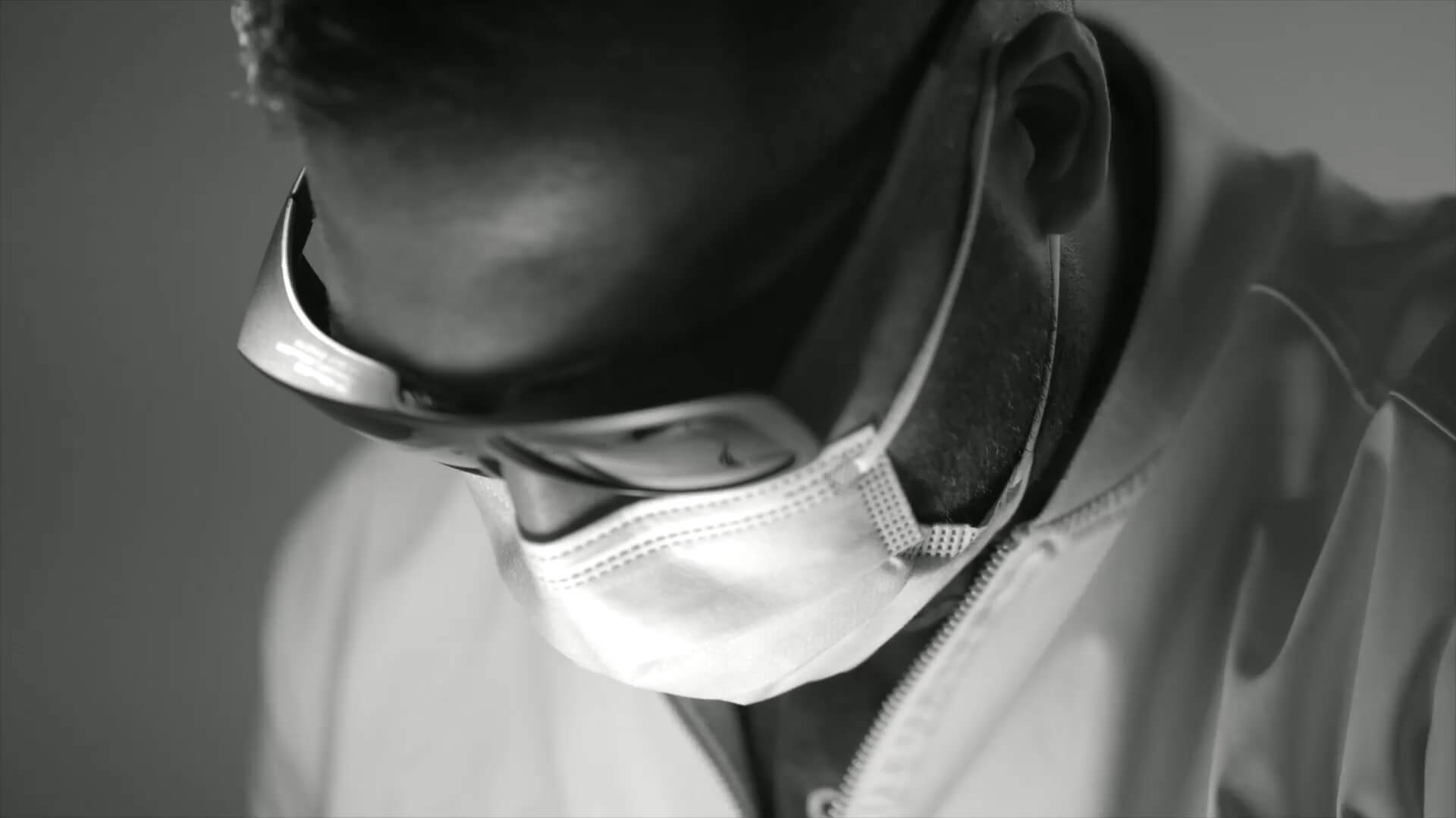 Close-up of a man wearing safety goggles and a face mask, focused downward.