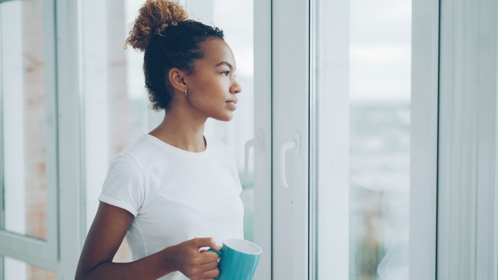 Woman holding a mug at a bright morning window