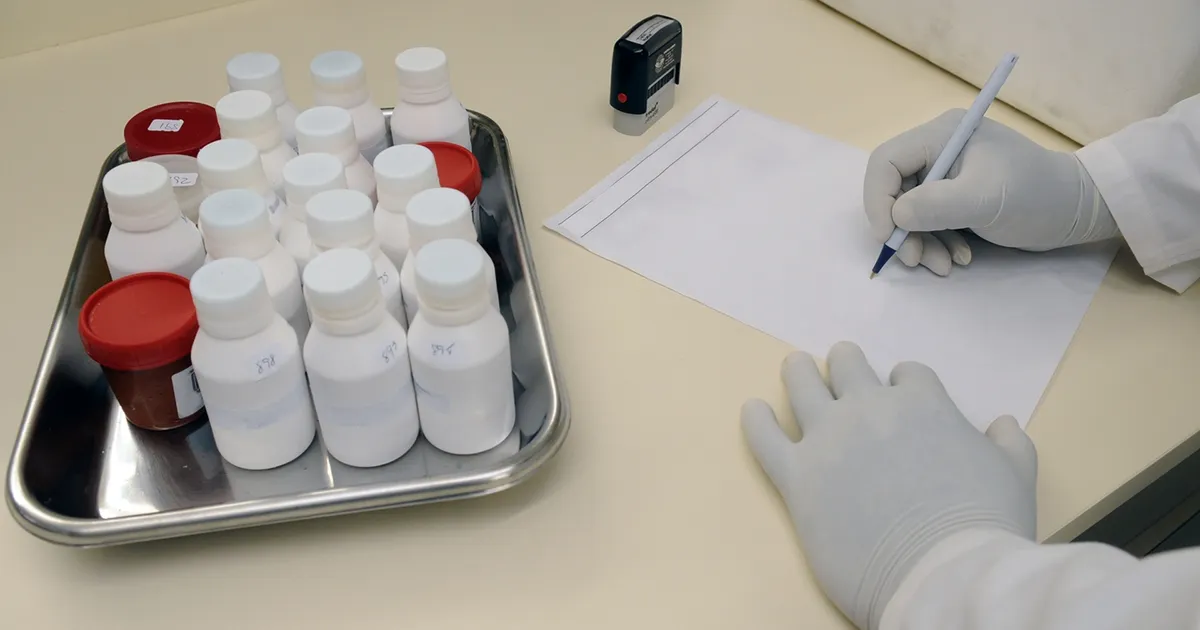 Laboratory sample containers on a tray beside a requisition form
