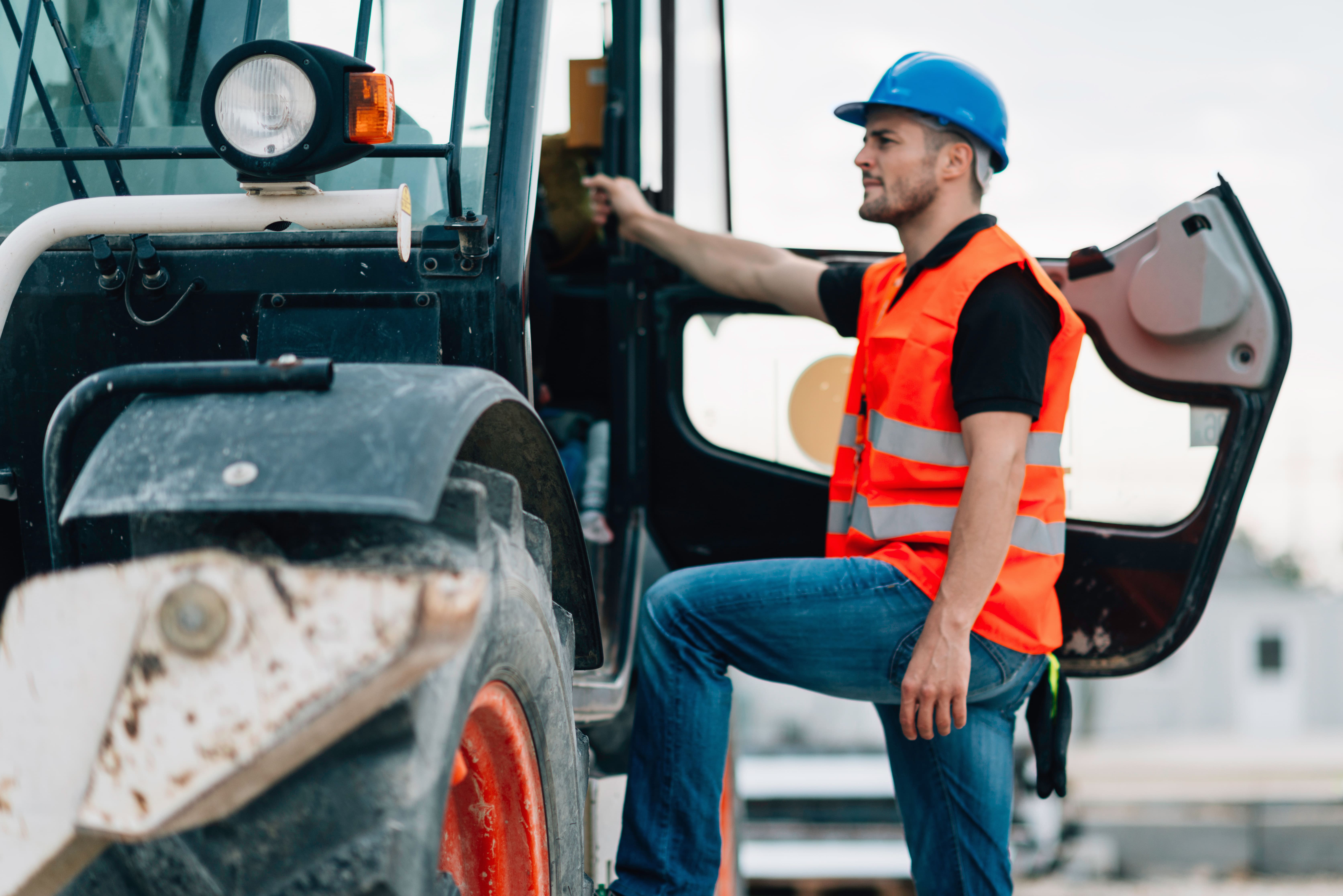 Hombre trabajador subiéndose a una plataforma articulada