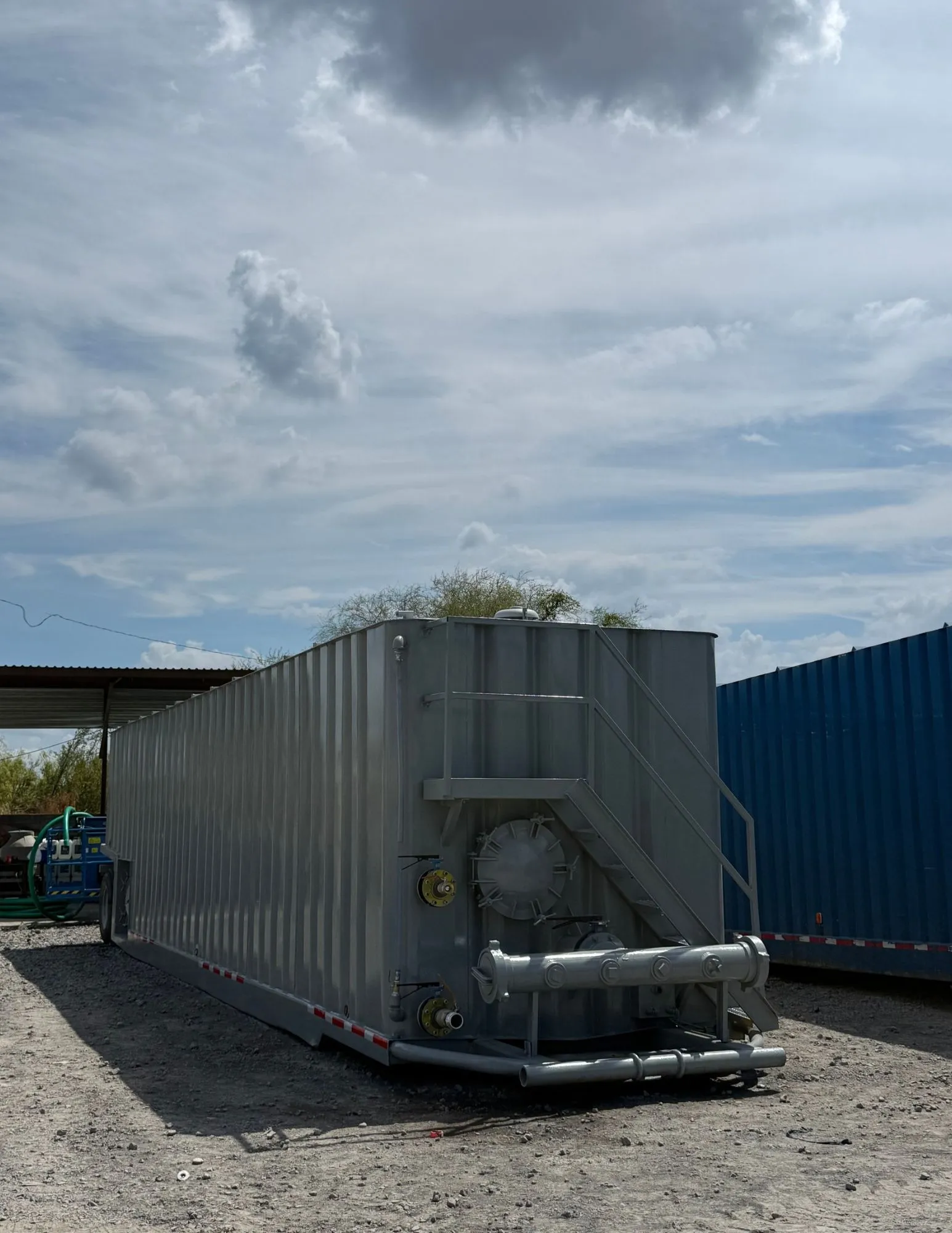 Frac tank de acero corrugado sobre remolque en patio de equipos, con escalera y manifold de conexiones