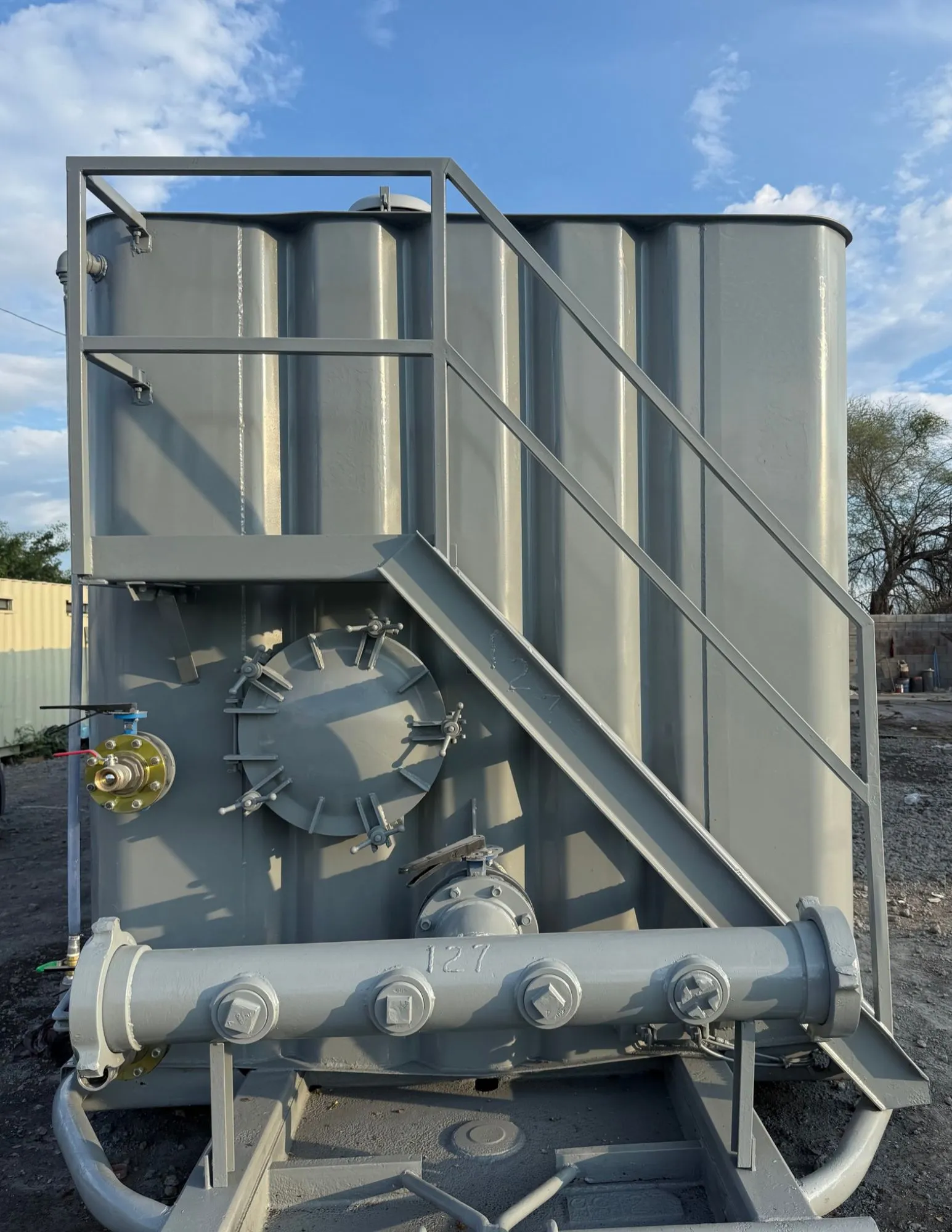Vista frontal de frac tank con manifold de cuatro conexiones, registro de hombre con tornillos mariposa y escalera