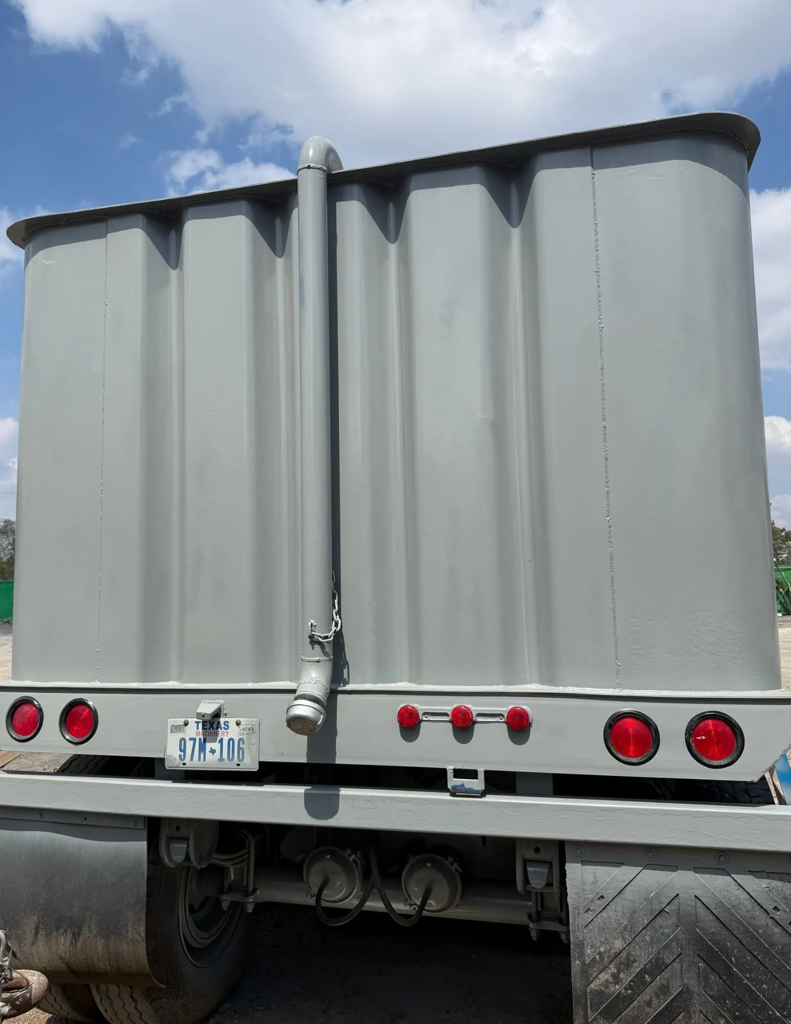 Frac tank gris con escalera, registro de hombre, válvula de mariposa y manifold de descarga en patio de equipos 3