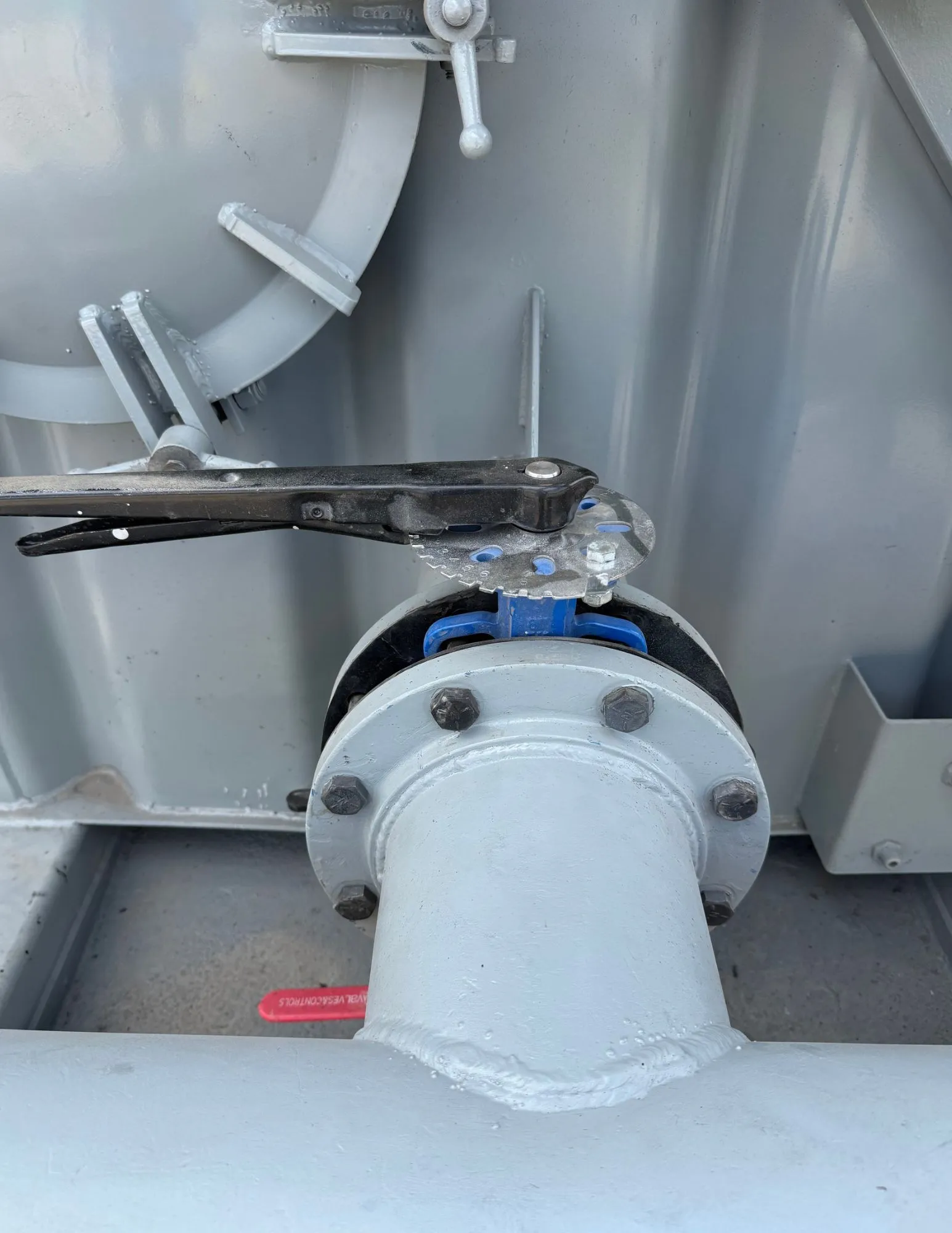 Frac tank gris con escalera, registro de hombre, válvula de mariposa y manifold de descarga en patio de equipos 4