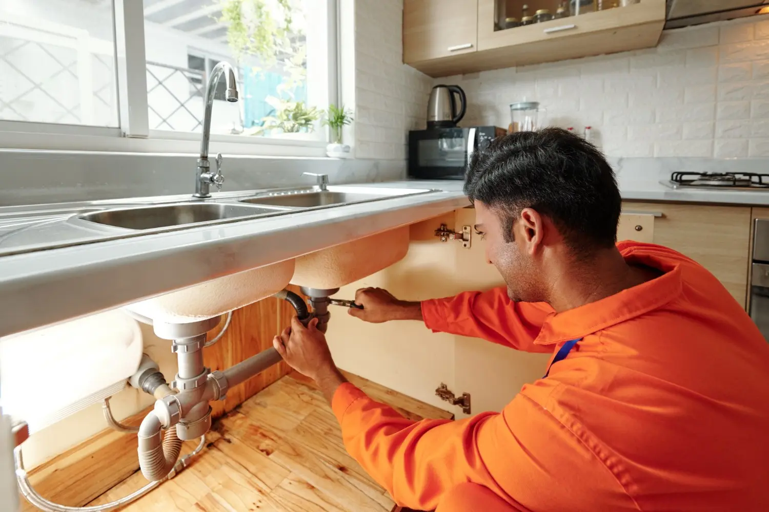 Image of a man working on kitchen plumbing