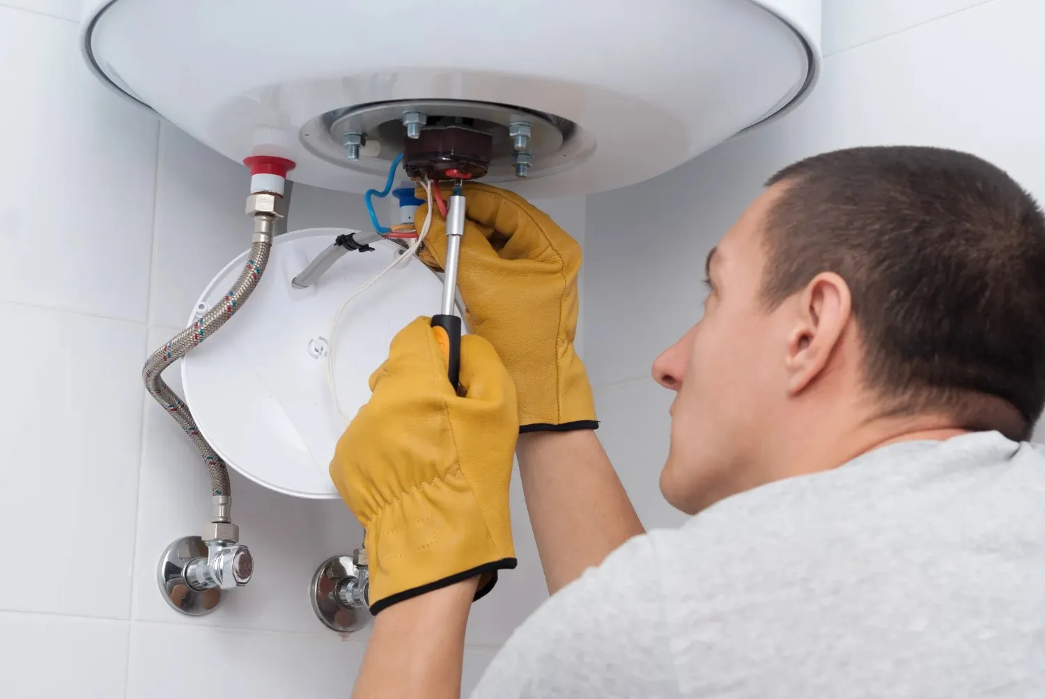 A person repairing a water heater system using tools