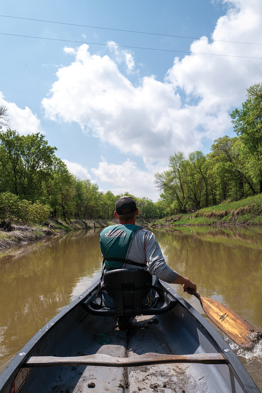 Person canoeing down a river in Minnesota on a sunny day.