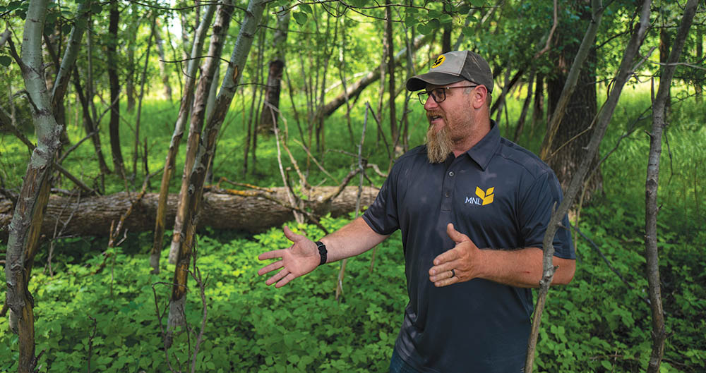 An employee representing MNL standing in a forest talking about their company.