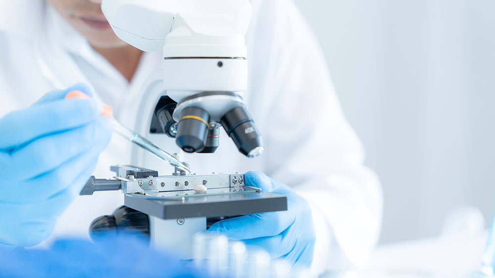 Person testing a sample under a microscope.