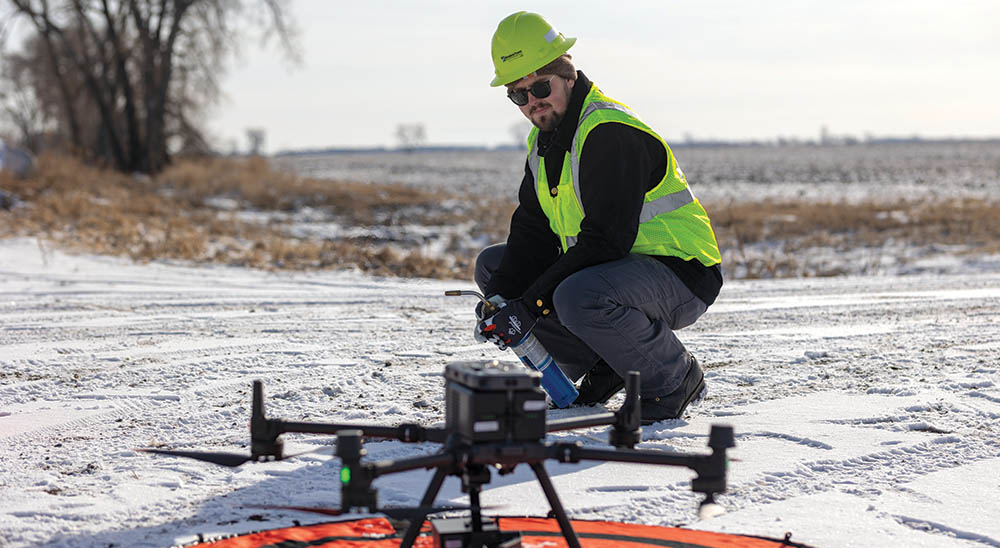 Minnkota employee setting up a drone out in an open field in winter.