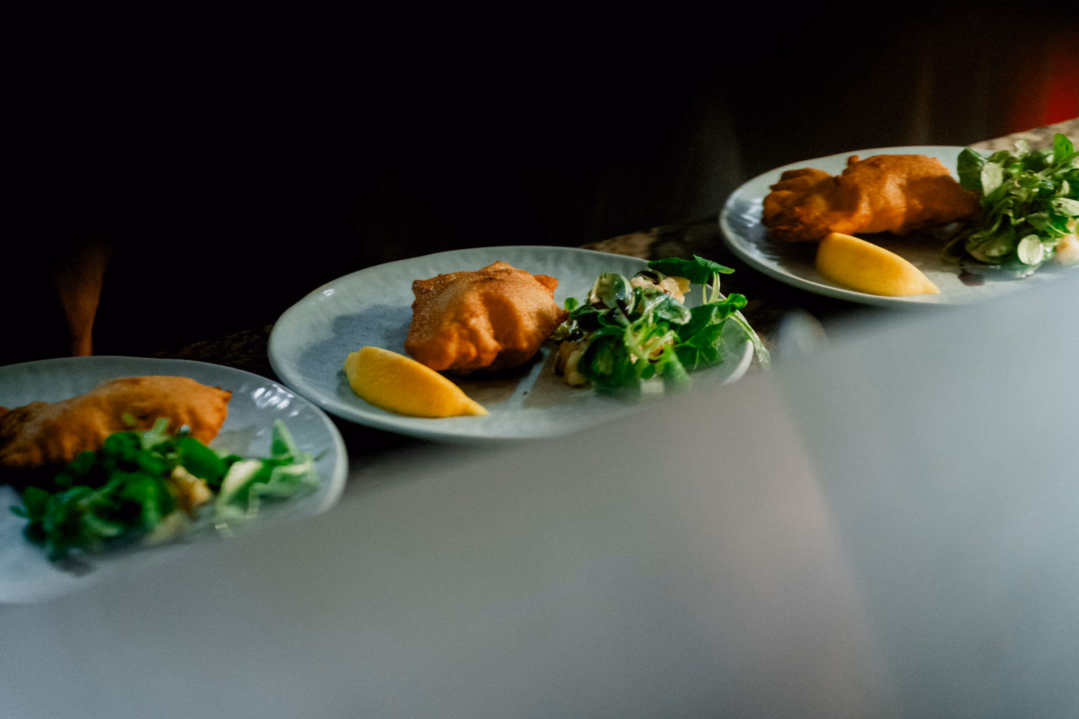 Drei Teller mit Wiener Schnitzel, Zitronenscheiben und gemischtem grünen Salat in Rubens Restaurant.