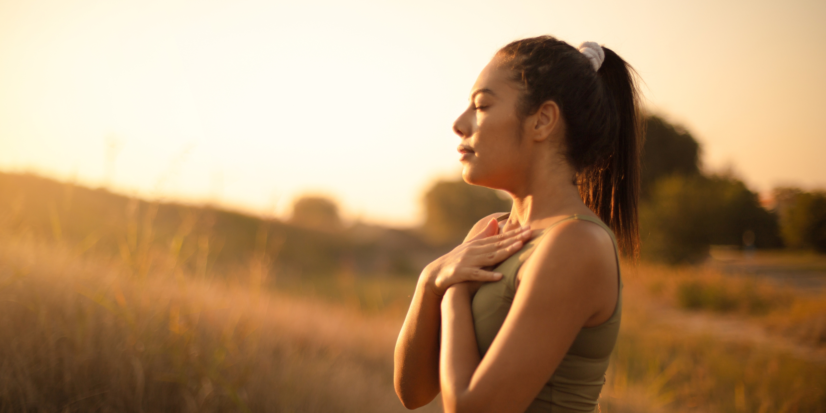 Femme dans un champs respirant les mains sur sa poitrine
