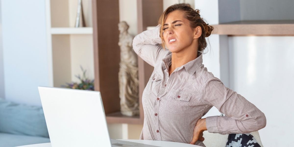 femme devant son ordinateur touchant sa nuque et son dos en douleur