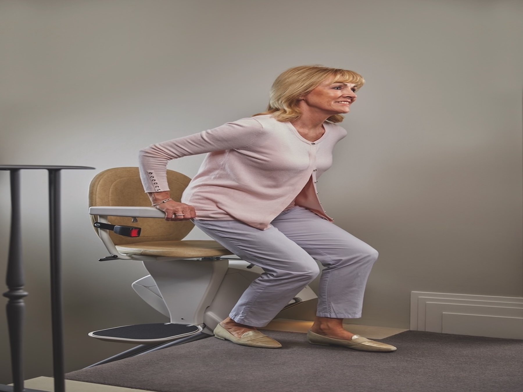 "Smiling woman using a home stairlift for safe and comfortable movement between floors"