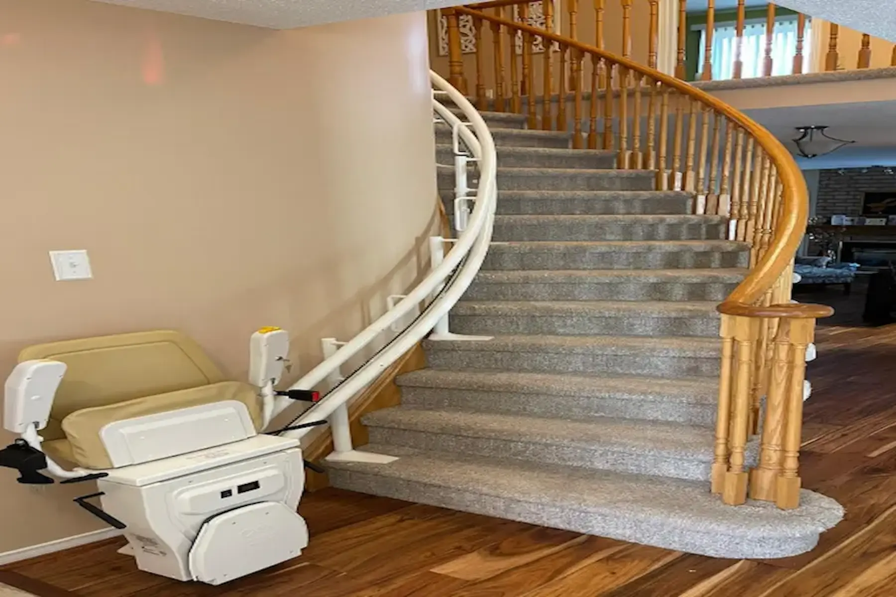 Curved stairlift installed on a carpeted staircase with wooden handrails in a modern home.