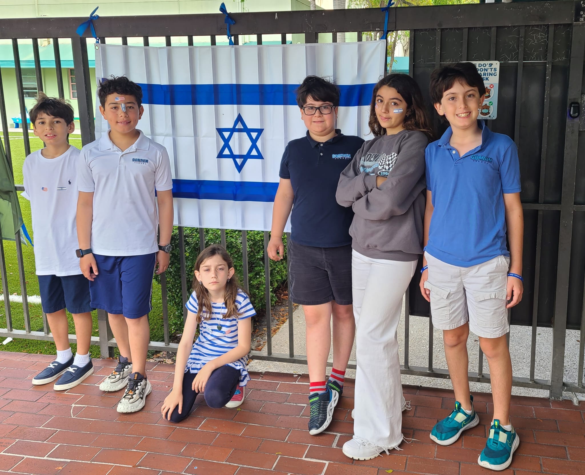 Center teens standing together in front of an Israeli flag