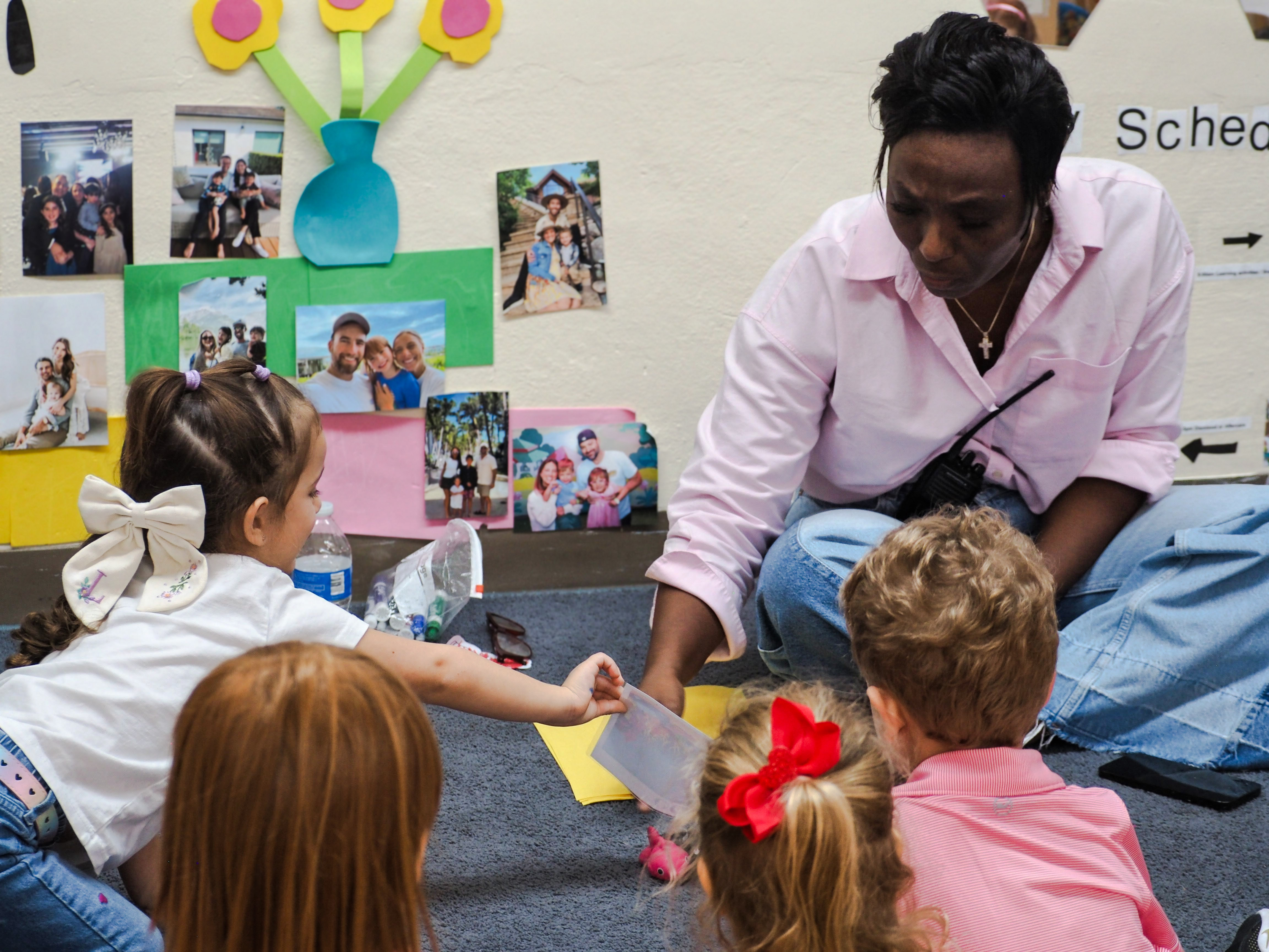 A teacher sits on the floor with young students during circle time