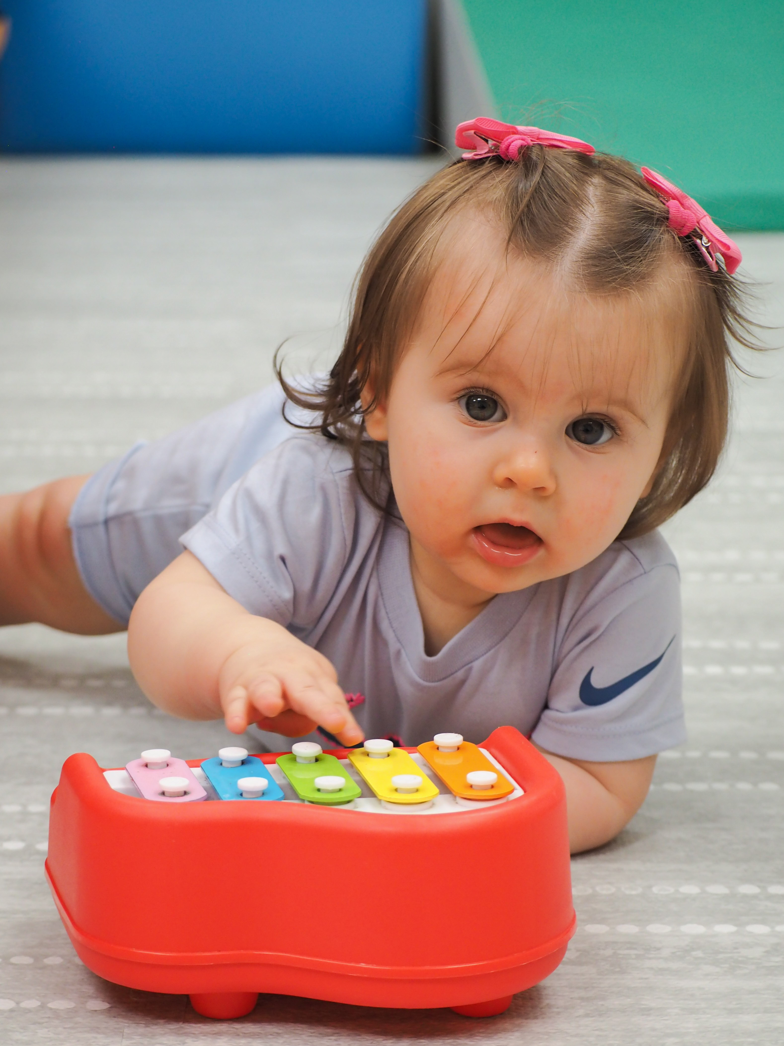 A Gordon infant playing a toy xylophone on the classroom floor