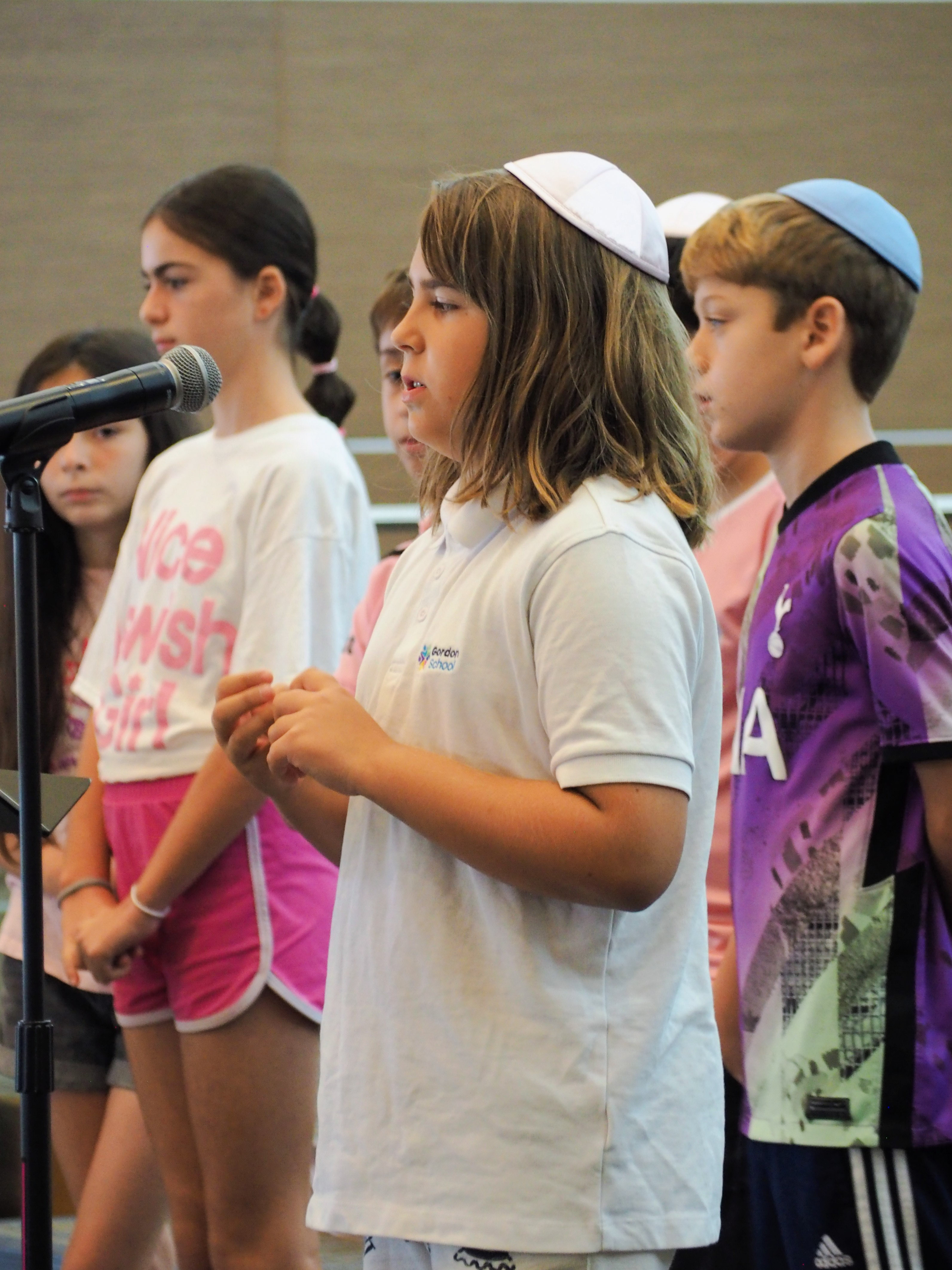 Gordon students in kippot singing together at a microphone