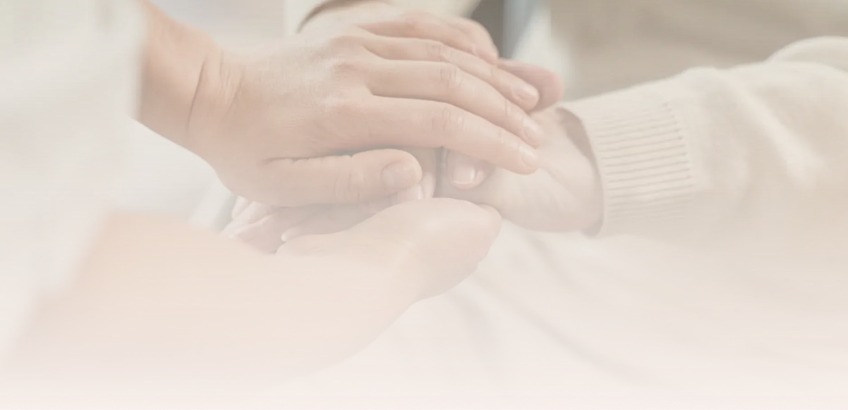 Two hands gently holding a patient's hand