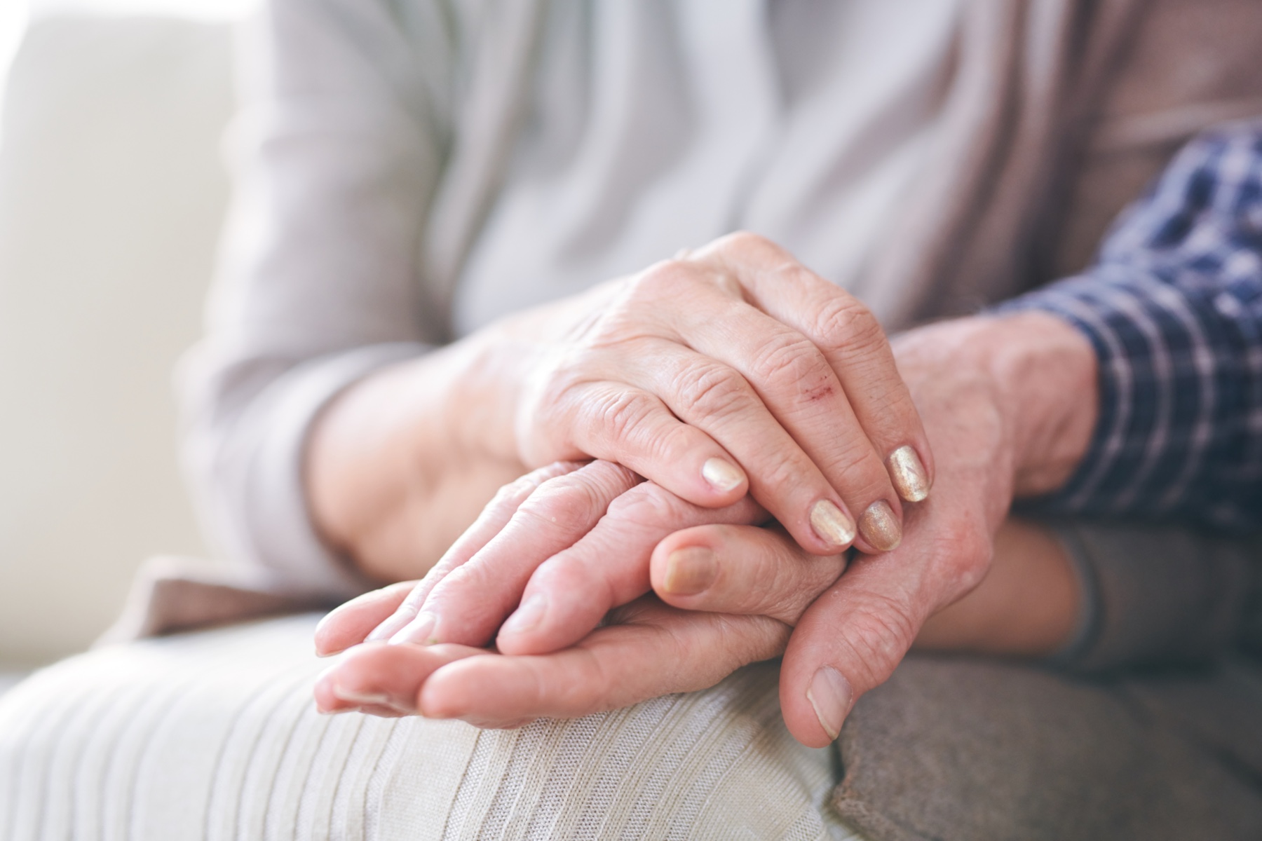An older couple sitting together, one holding the other's hands