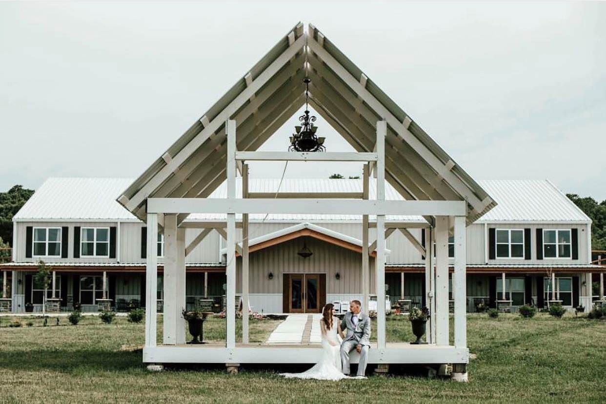 a newlywed couple sitting on a open white gazebo in front of the Deer Ridge Estate