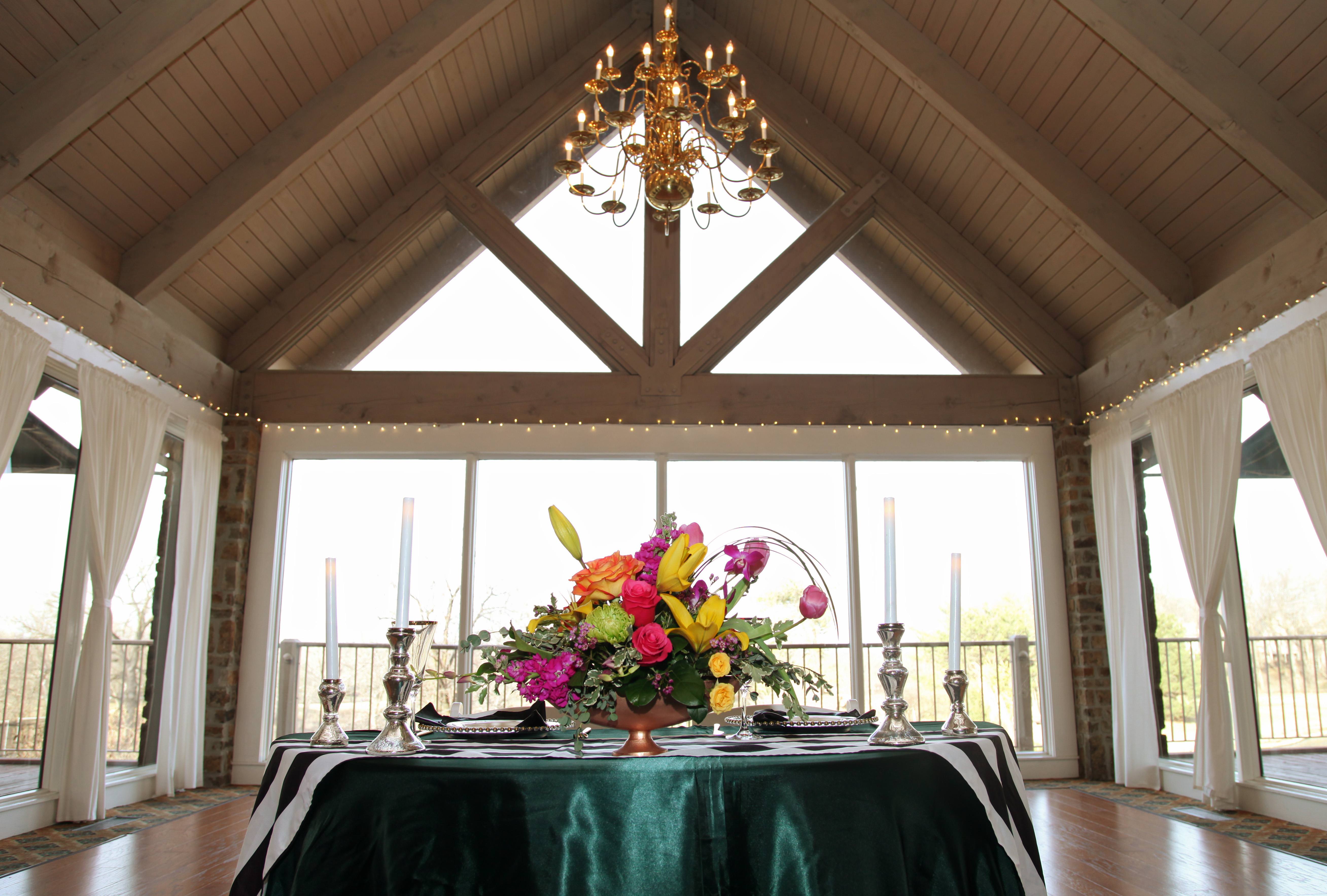 a head table for a wedding with deep shimmery green table cloths with silver centerpieces and flatware