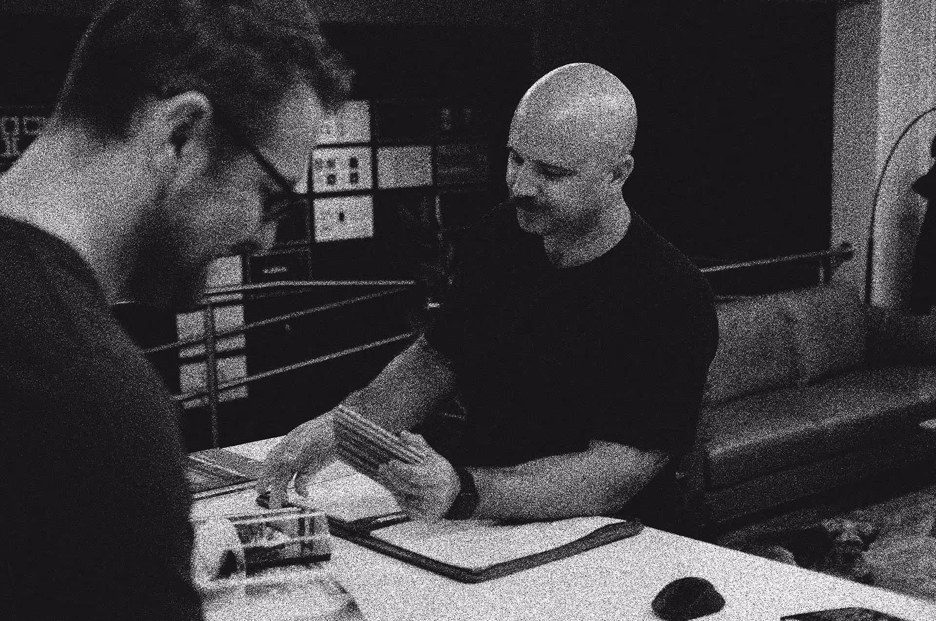 Black and white image of architects collaborating over building plans and documents in a contemporary office setting.