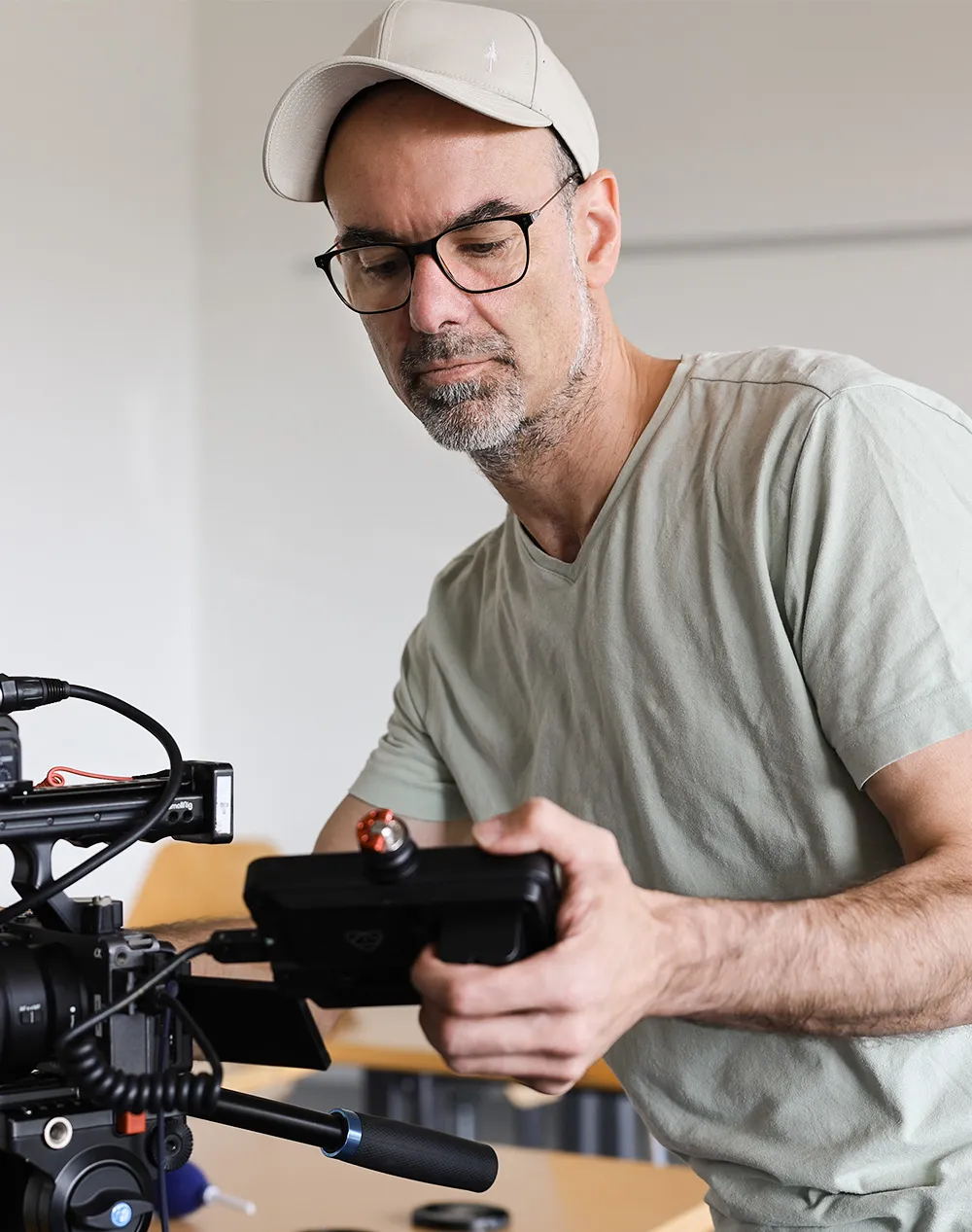 Florian Wyss mit Brille und Basecap bedient eine professionelle Filmkamera in einem Raum.