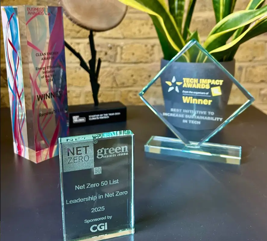 Renewabl awards | Four environmental and sustainability awards displayed on a table, including a Net Zero 50 List award for Leadership in Net Zero 2025 sponsored by CGI, Tech Impact Awards Winner for best initiative to increase sustainability in tech, Clean Energy Award for Energy Efficiency Initiative of the Year 2024, and a round item in black stand.