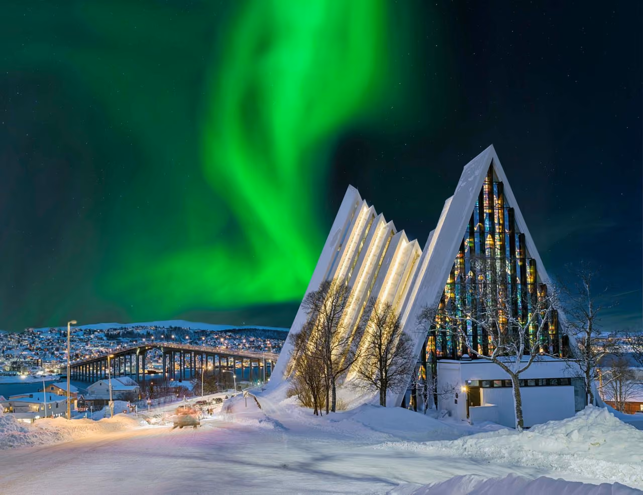 Church in tromsø with the northern lights dancing on the dark sky behind