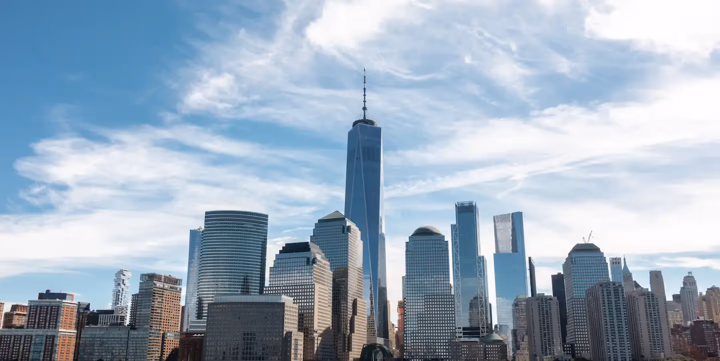 Skyline of tall modern skyscrapers under blue sky with wispy clouds.