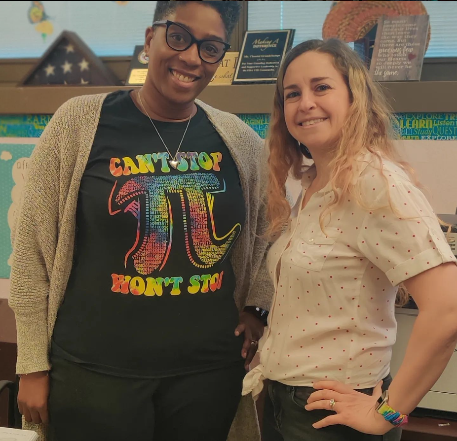 Two smiling staff members posing together in a classroom