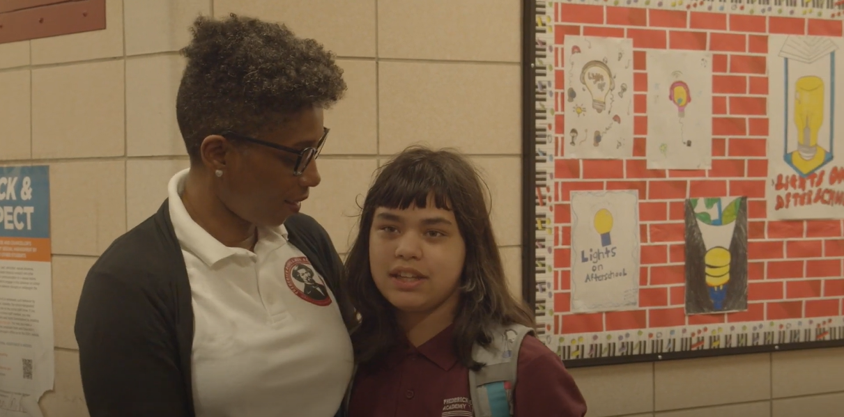Teacher placing a supportive hand on a student's shoulder in hallway