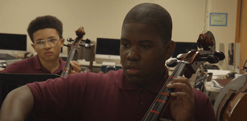 Two students playing cellos during school orchestra class