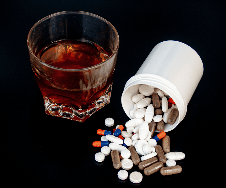 A glass of alcohol and pills on the table