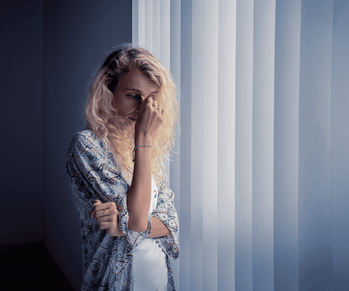 Desperate young woman standing near the window