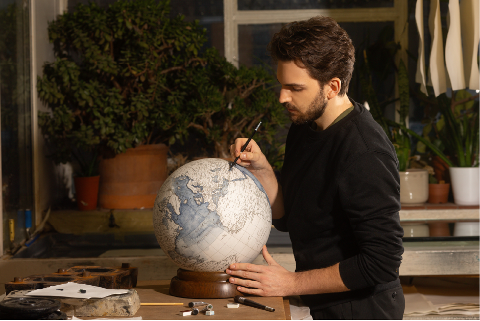 Leonardo Frigo painting and handmade globe in his studio in London