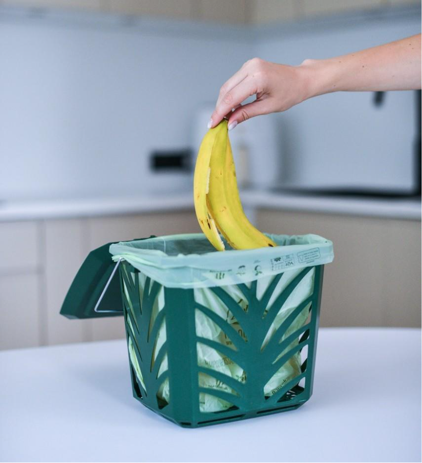 A hand holding a banana in a green basketAI-generated content may be incorrect.