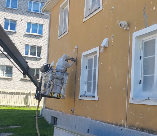 A person in a bucket painting a buildingAI-generated content may be incorrect.