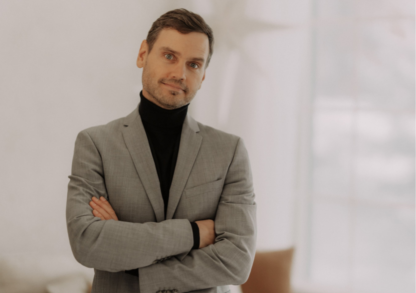 A person in a suit with his arms crossedAI-generated content may be incorrect.