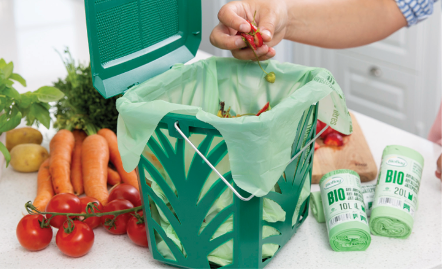 A person putting a small red pepper into a green trash canAI-generated content may be incorrect.