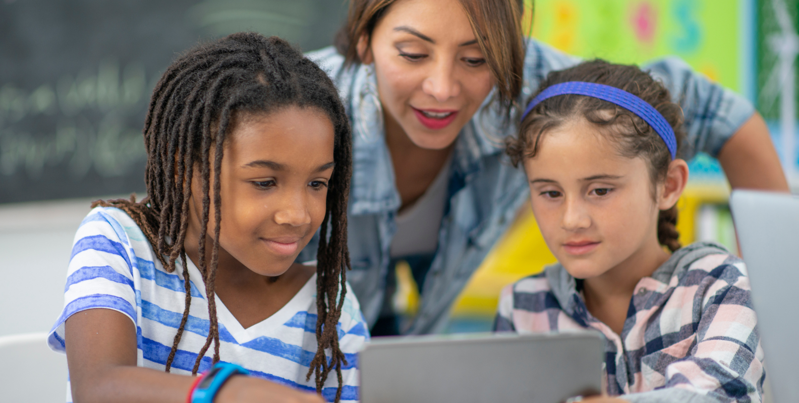 Eine Lehrerin und Schüler vor einem Tablet