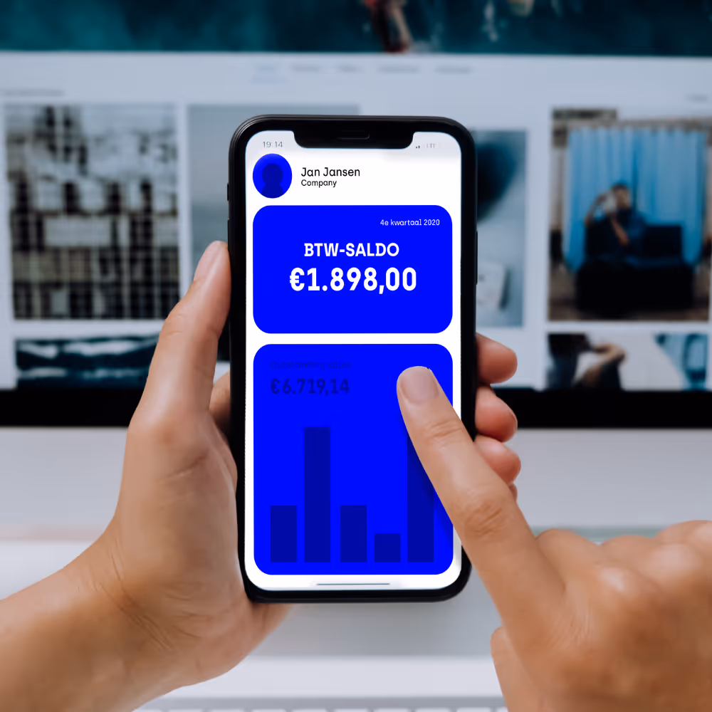 Hand die een smartphone vasthoudt met een financieel overzicht van Jan Jansen met BTW-saldo en uitstaande verkopen in bar chart.