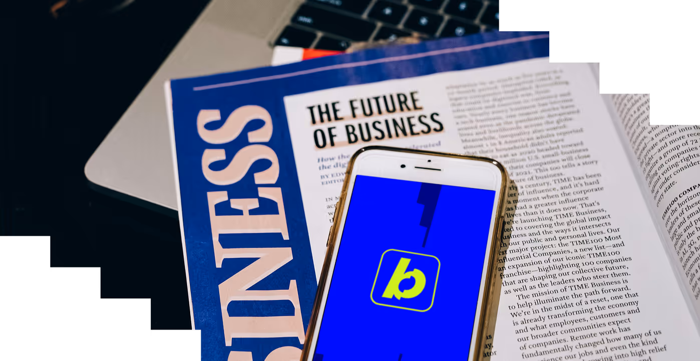 Smartphone met een blauwe achtergrond en een geelgroen logo ligt op een open zakenmagazine met de kop 'The Future of Business'.