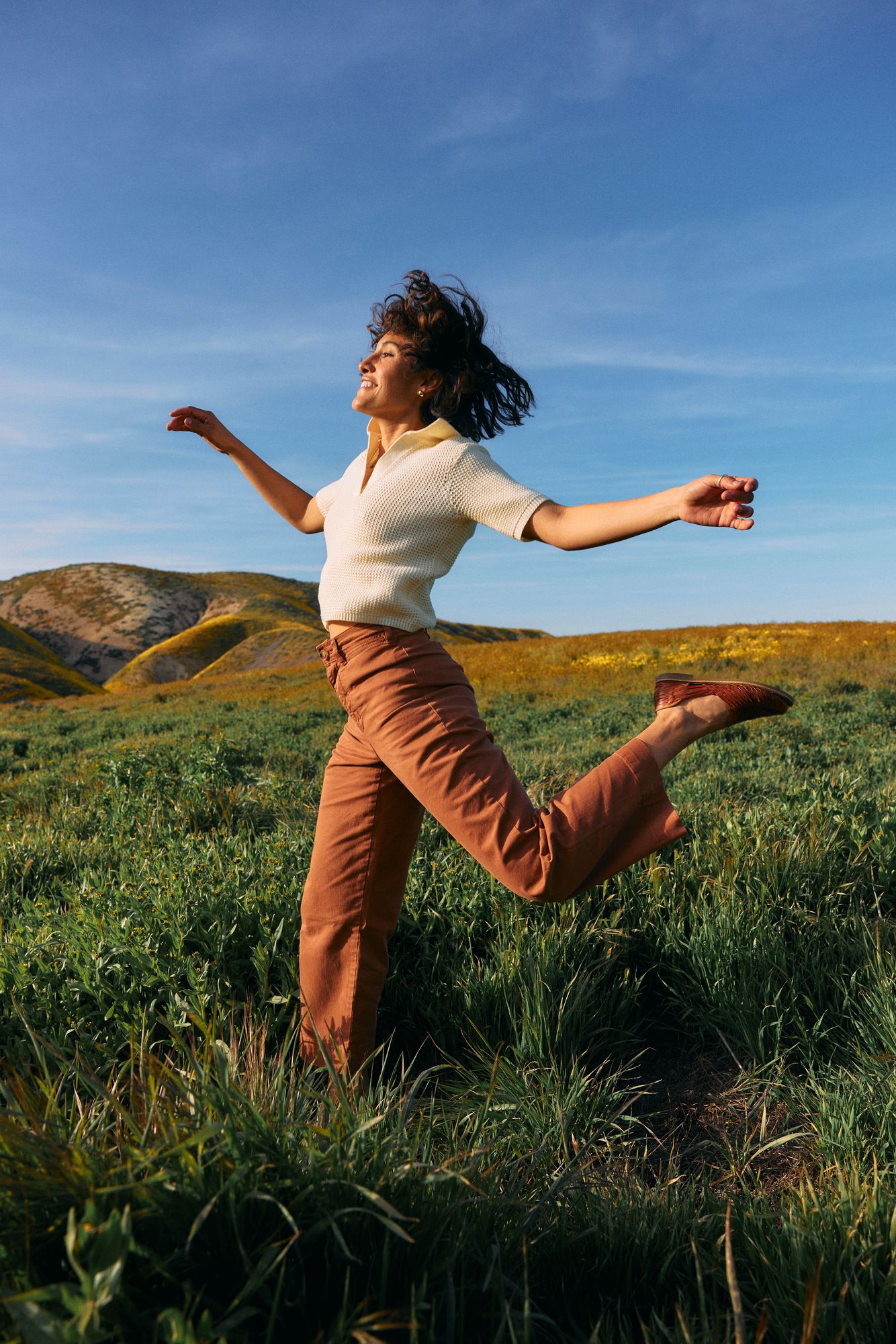 Woman jumping joyfully in a field, pain-free and active after regenerative treatment