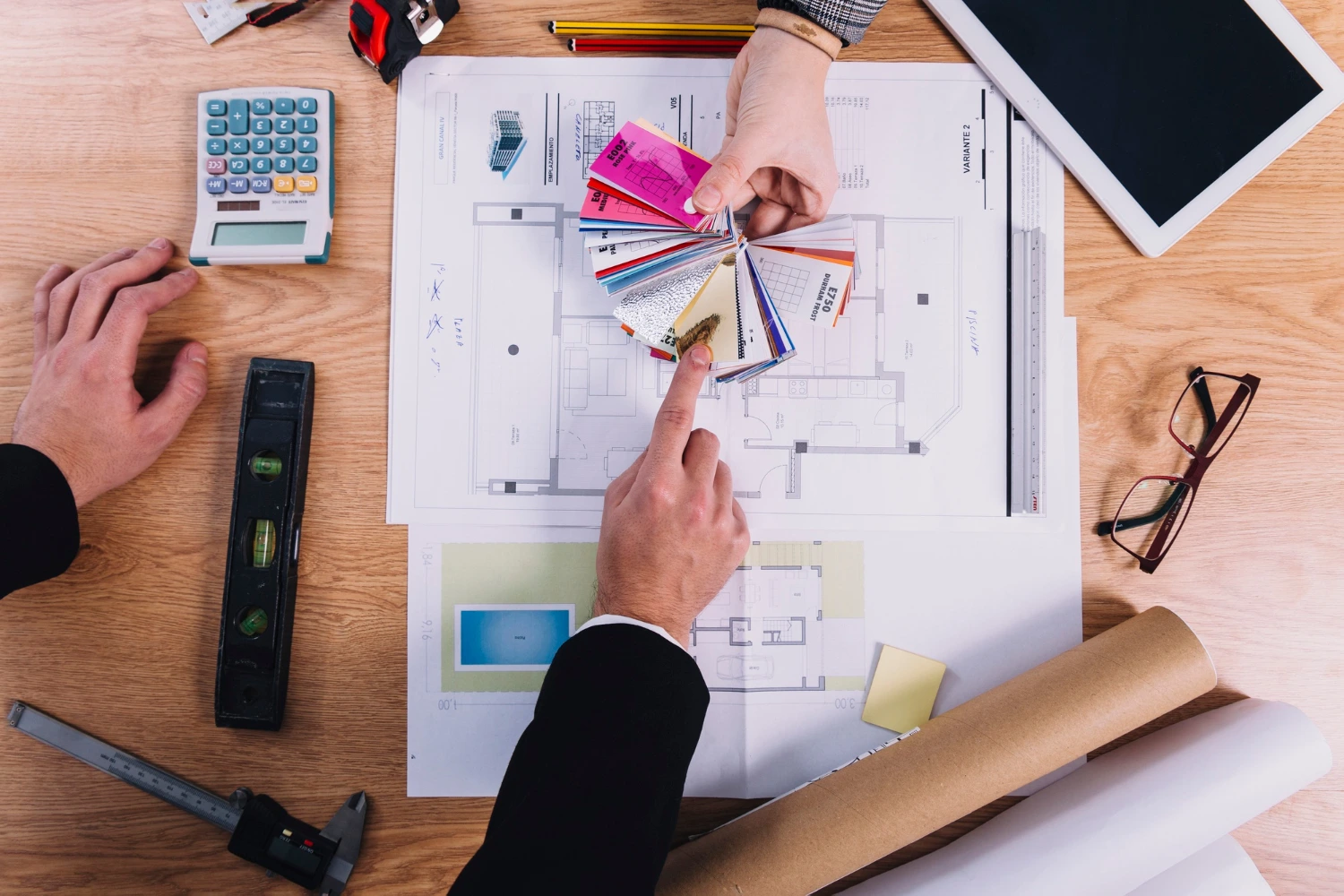 Build Solutions, commercial contractor reviewing building plans, material samples, and project costs with client at desk—representing trust, transparency, and professional planning in Los Angeles.
